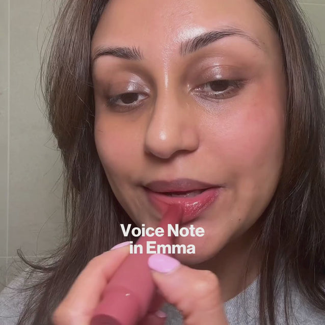 Woman applying Voice Note Tinted Lip Treatment Balm in Emma as a lip and cheek balm, layered under Mega Bite lip oil