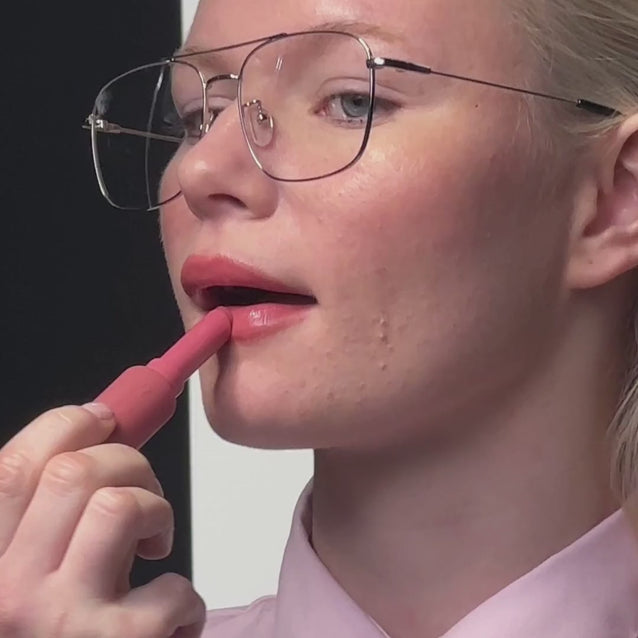 Model using Voice Note Tinted Lip Treatment Balm in Macaron as a cheek balm and lip tint for a rosy flush