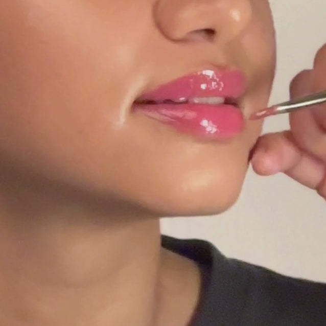 Model applying Mega Bite Tinted Jelly Lip Oil in Macaron for glossy pink lips